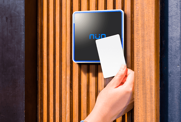 Mano acercando una tarjeta de proximidad a una lector de control de acceso de la marca NÜO